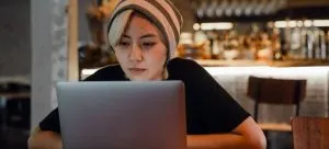 A woman sitting in a cafe and using a laptop for research when moving from the USA to Hong Kong. 