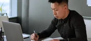 A man writing in a notebook items, which is one of the tips for storing items during a home renovation.