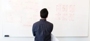 A man standing in a front of a whiteboard and setting goals, which is important when moving abroad for the first time. 