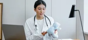 A doctor holding a teddy bear.