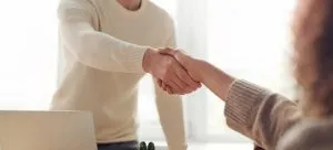 Two people shaking hands at the job interview. To adapt to the UK with ease, look for job opportunities.