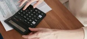 A woman using a calculator to set the budget for moving from Hong Kong to Australia.