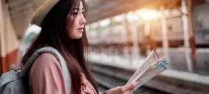 A woman on a station holding a map. If you consider the process an adventure, international move can become a fun experience.